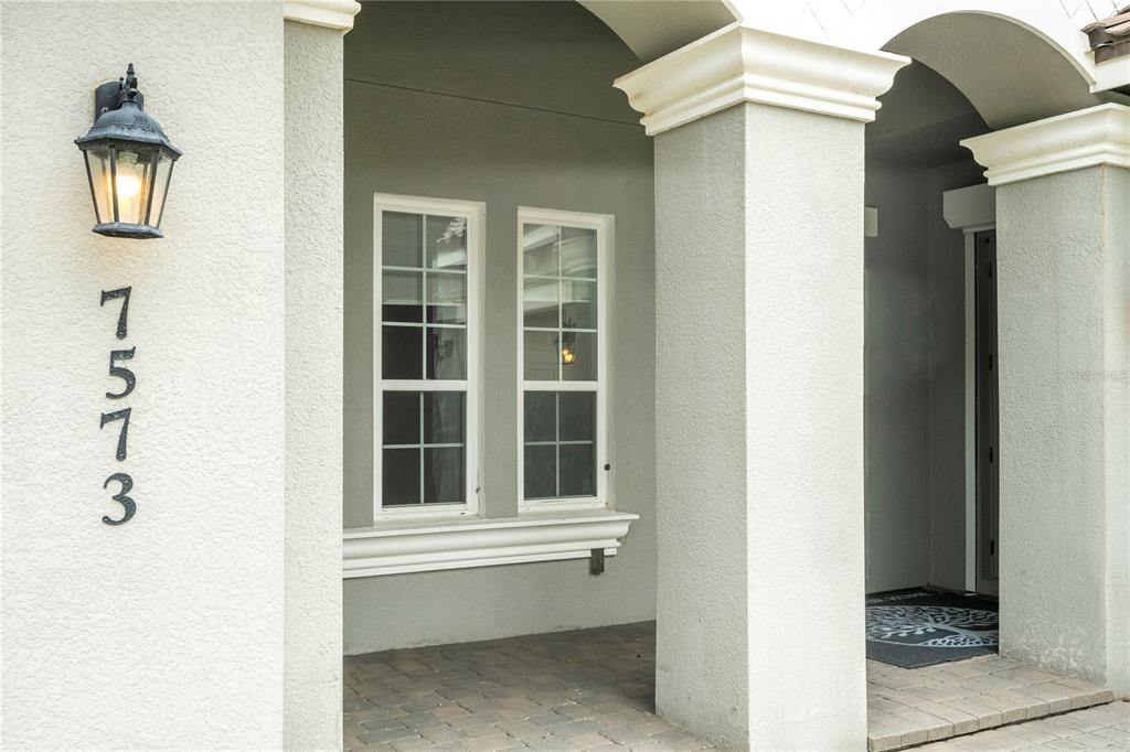 A covered entryway features a stucco wall with house numbers, a wall lamp, and columns — 7573 GREEN MOUNTAIN WAY, WINTER GARDEN, FL