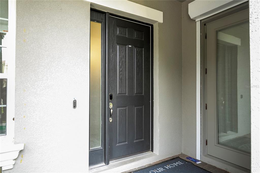 A front entryway features a dark paneled door with a sidelight and a glass storm door — 7573 GREEN MOUNTAIN WAY, WINTER GARDEN, FL