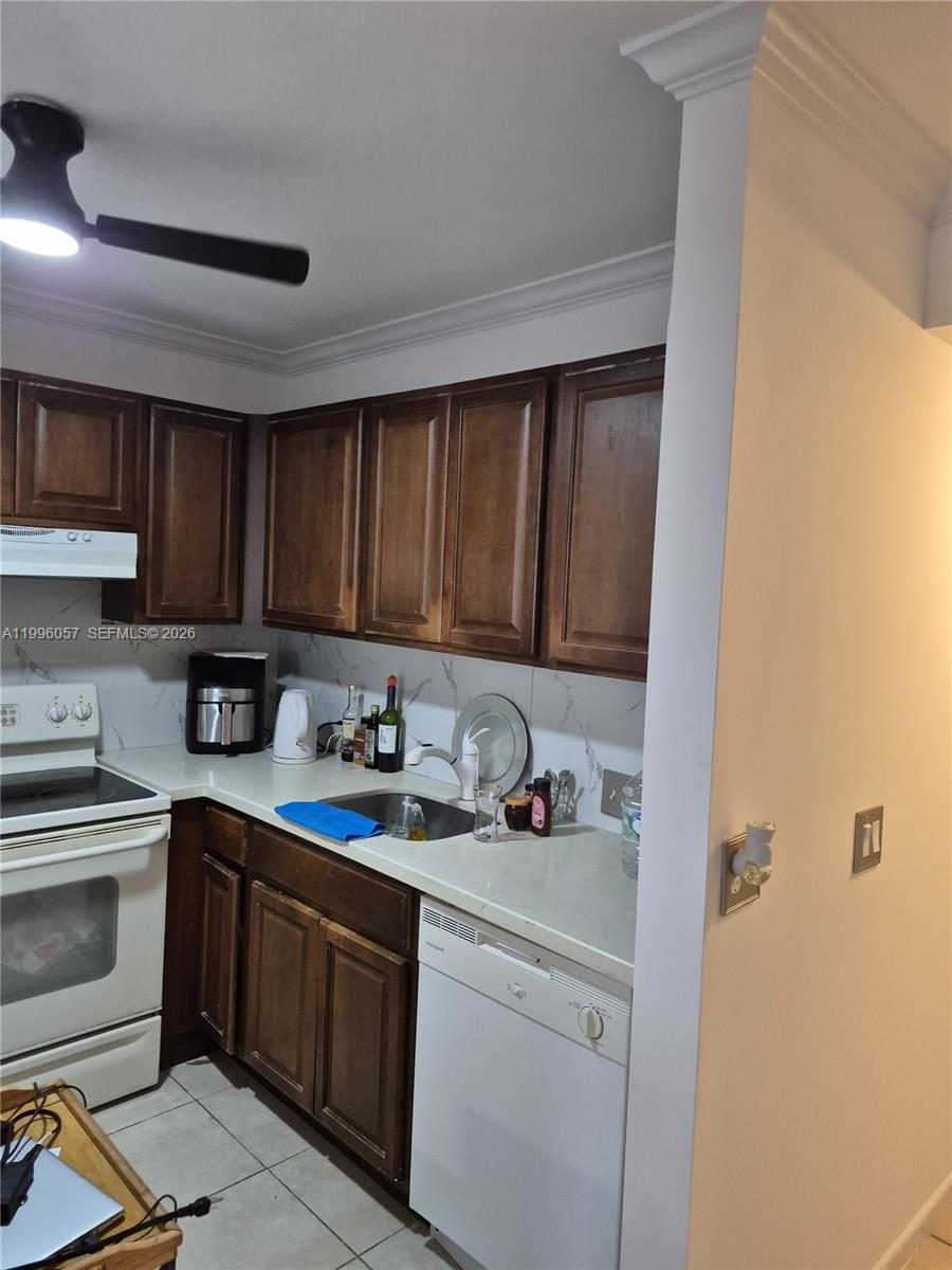 A kitchen features dark wood cabinets, white countertops, a white dishwasher, and a white stove — 371 brighton I # 371, Boca Raton FL 33434, BOCA RATON, FL