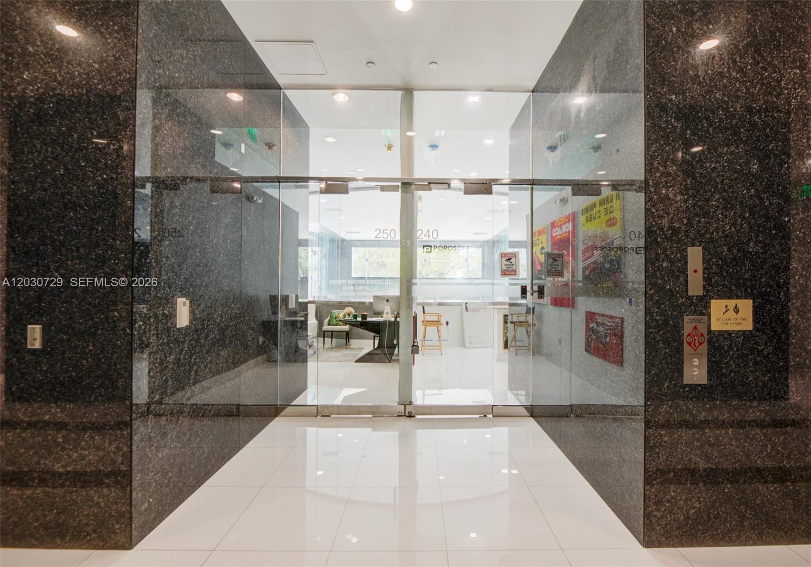 A glass-fronted office entrance features dark granite walls and a white tiled floor — 1200 Brickell Ave # K, Miami FL 33131, MIAMI, FL