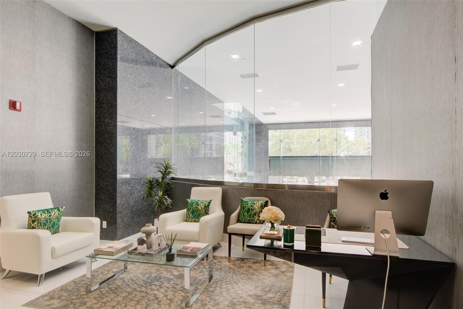 A modern office features white armchairs, a glass coffee table, and a desk with a computer — 1200 Brickell Ave # K, Miami FL 33131, MIAMI, FL