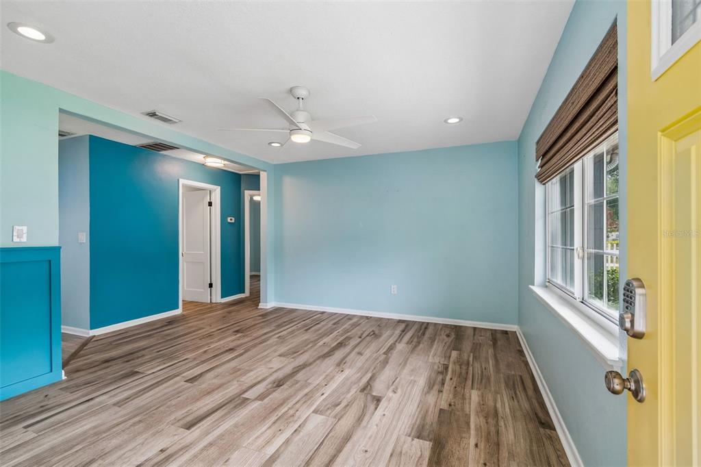 An interior view of a living room with light blue walls, wood-look flooring, and a door — 1304 E KNOLLWOOD STREET, TAMPA, FL