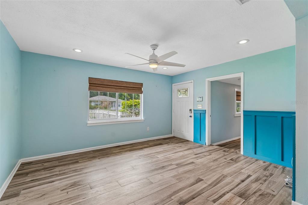 An empty room features light blue walls, wood-look flooring, a ceiling fan, and wainscoting — 1304 E KNOLLWOOD STREET, TAMPA, FL