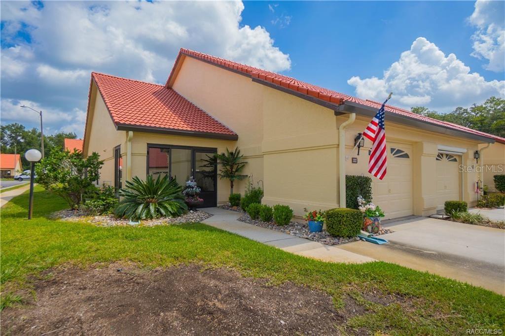 A single-story tan villa with a red tile roof, a garage, and a front walkway — 2022 FOREST DRIVE, INVERNESS, FL