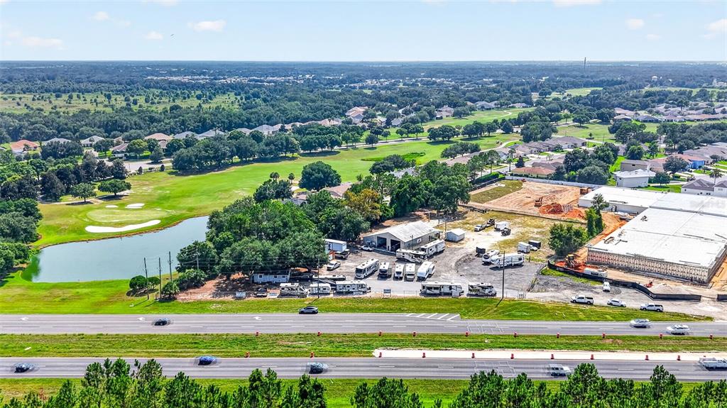 An aerial view shows a commercial property with RVs parked near a pond and golf course — 27101 US HIGHWAY 27, LEESBURG, FL
