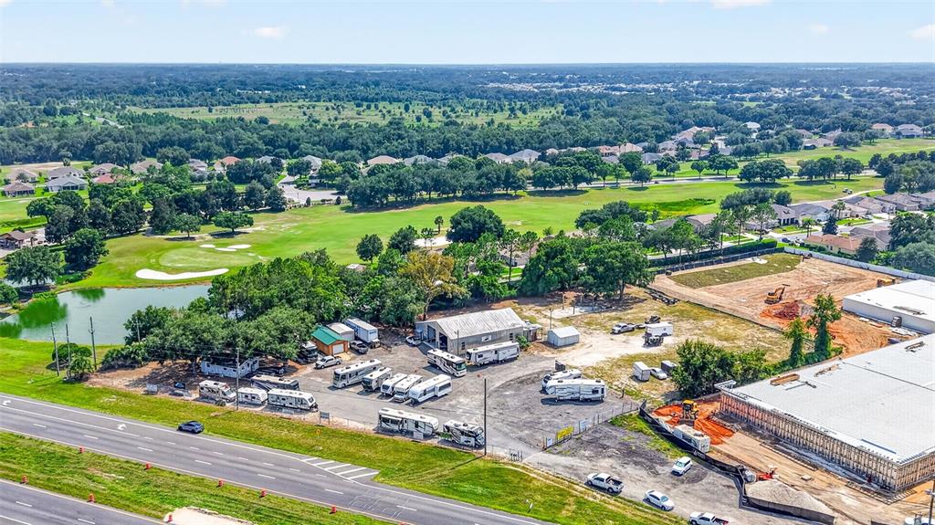 An aerial view shows a gravel lot with parked RVs next to a large warehouse — 27101 US HIGHWAY 27, LEESBURG, FL