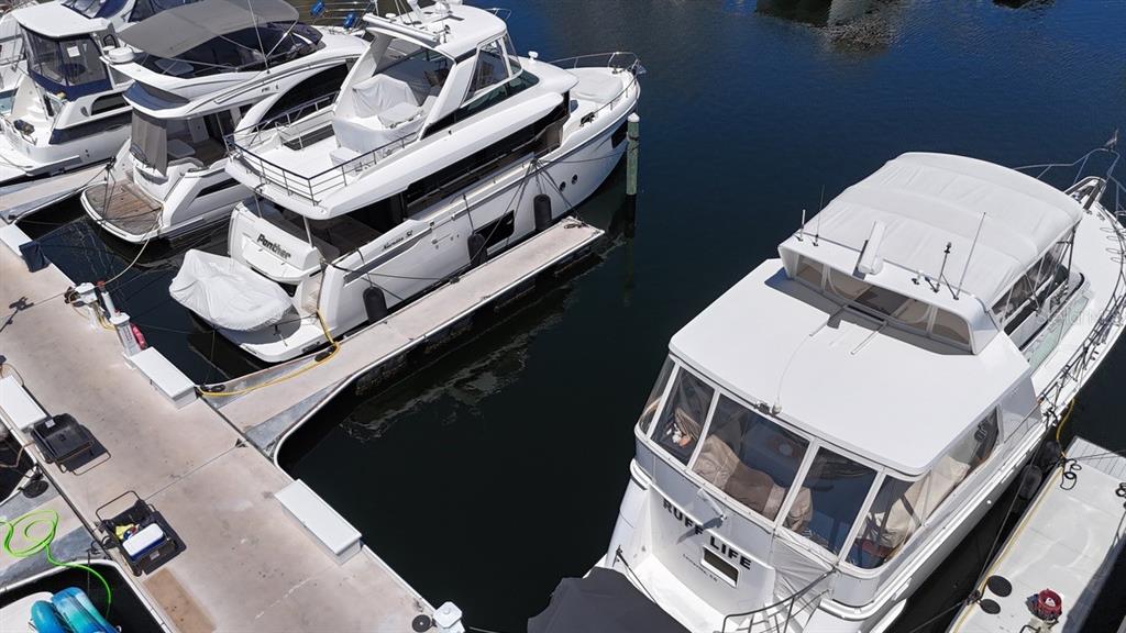 An aerial view shows three white yachts docked at a marina on a sunny day — 102 RIVIERA DUNES WAY UNIT C-7, PALMETTO, FL