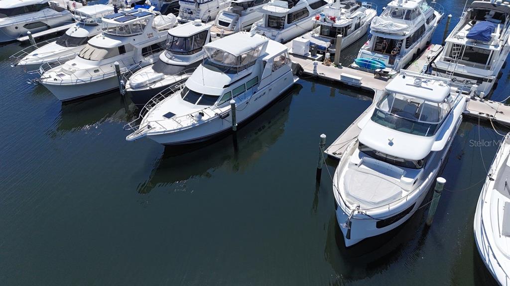 An aerial view shows several white motor yachts docked in a marina on calm water — 102 RIVIERA DUNES WAY UNIT C-7, PALMETTO, FL
