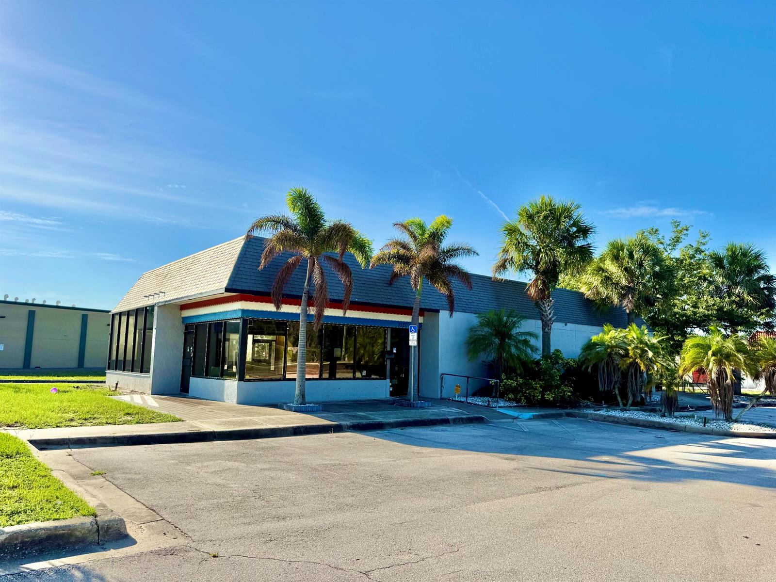 A single-story commercial building with a gray roof and palm trees in the parking lot — 1520 Lakeview Drive, Sebring FL 33870, SEBRING, FL