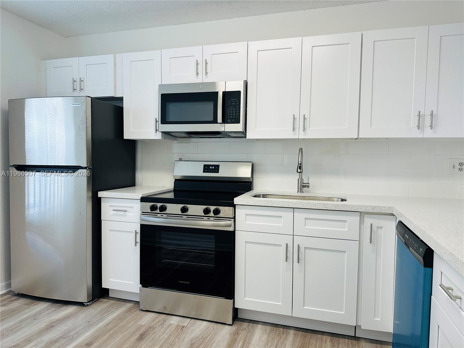 A kitchen features white cabinets, stainless steel appliances, a white backsplash, and light wood flooring — 8102 SW 21st Ct # 8102, Miramar FL 33025, MIRAMAR, FL