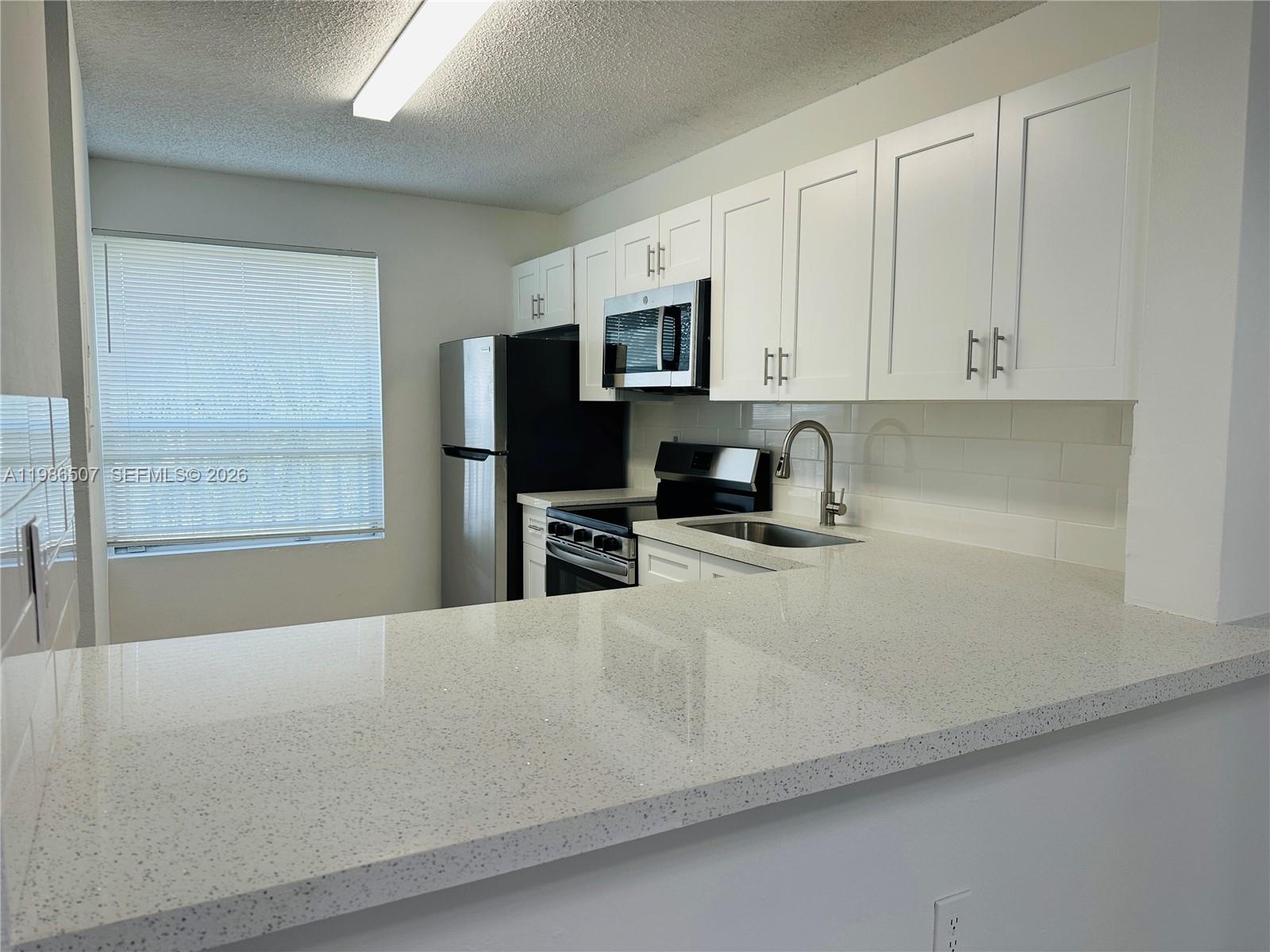 A kitchen features white cabinets, quartz countertops, stainless steel appliances, and a subway tile backsplash — 8102 SW 21st Ct # 8102, Miramar FL 33025, MIRAMAR, FL