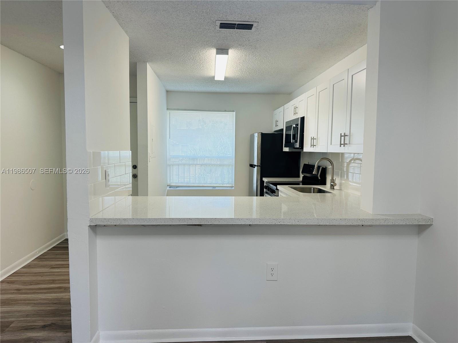 A kitchen features white cabinets, a quartz countertop, and stainless steel appliances — 8102 SW 21st Ct # 8102, Miramar FL 33025, MIRAMAR, FL