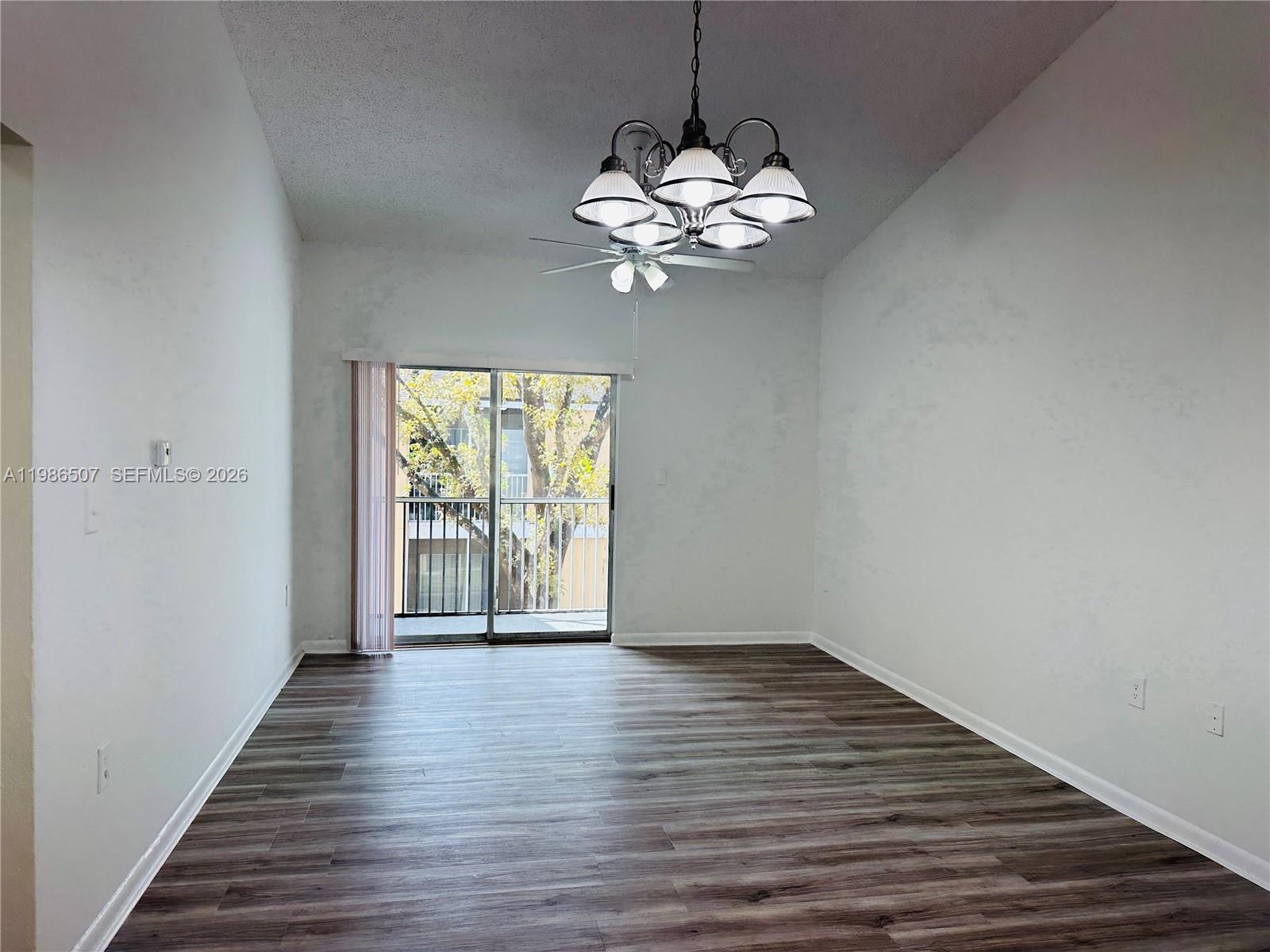 An empty room features wood-look flooring, a chandelier, a ceiling fan, and a sliding door — 8102 SW 21st Ct # 8102, Miramar FL 33025, MIRAMAR, FL