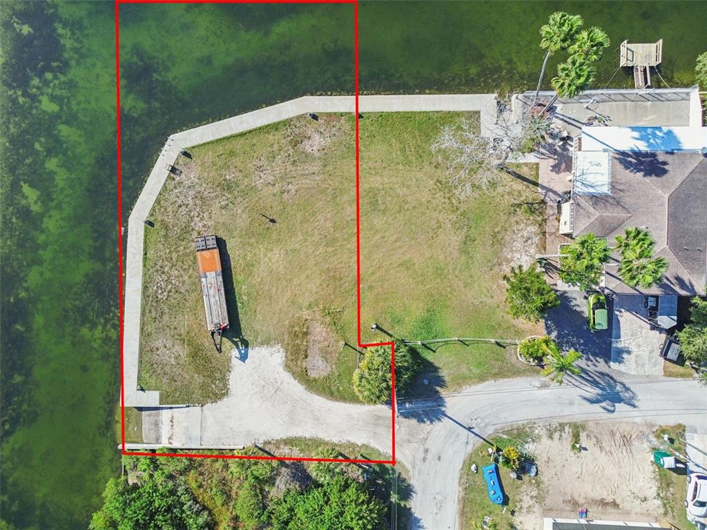 An aerial view shows a waterfront lot with a concrete seawall, boat ramp, and driveway — 6374 BOATYARD DRIVE, HUDSON, FL