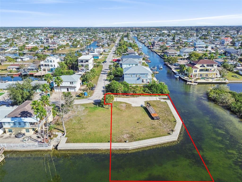 An aerial view shows a vacant waterfront lot outlined in red along a canal — 6374 BOATYARD DRIVE, HUDSON, FL