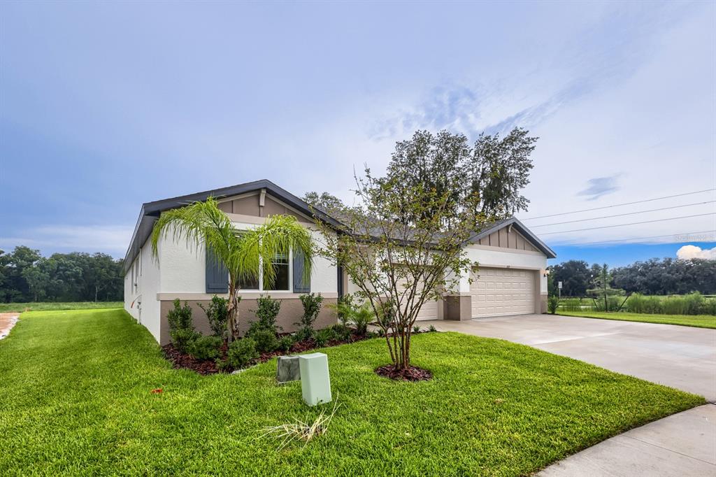 A single-story house with a two-car garage, light-colored stucco siding, and a landscaped front yard — 3819 ORANGE FOREST LANE, BARTOW, FL