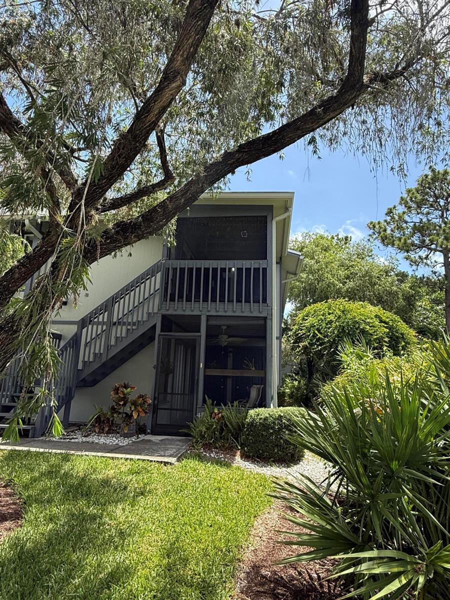 A two-story building with a screened-in balcony and staircase surrounded by trees and landscaping — 8228 SE Croft Circle # 8, Hobe Sound FL 33455, HOBE SOUND, FL