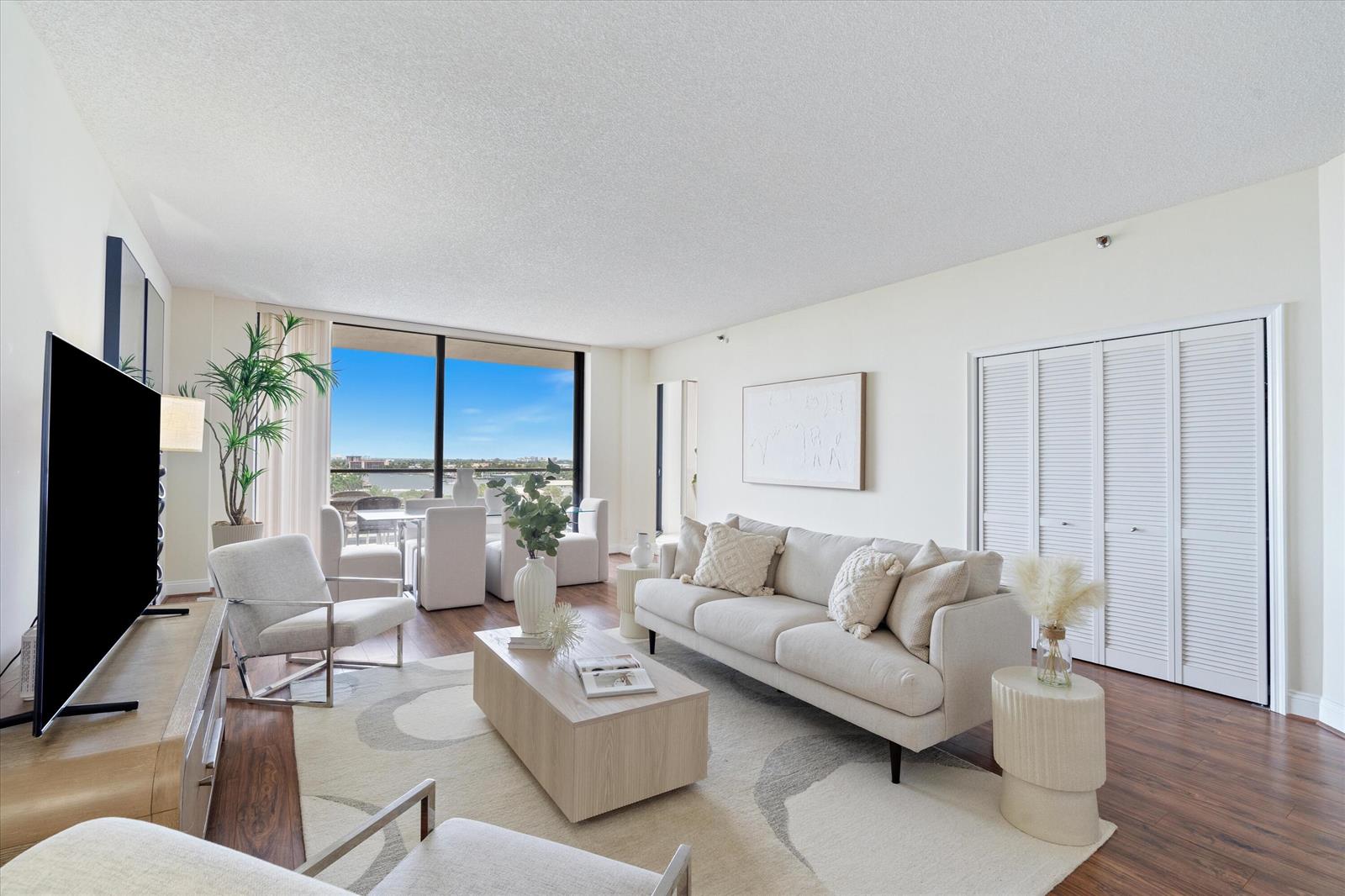 A bright living room features a beige sofa, wooden coffee table, and floor-to-ceiling windows — 1300 S Ocean Boulevard # 705, Pompano Beach FL 33062, POMPANO BEACH, FL