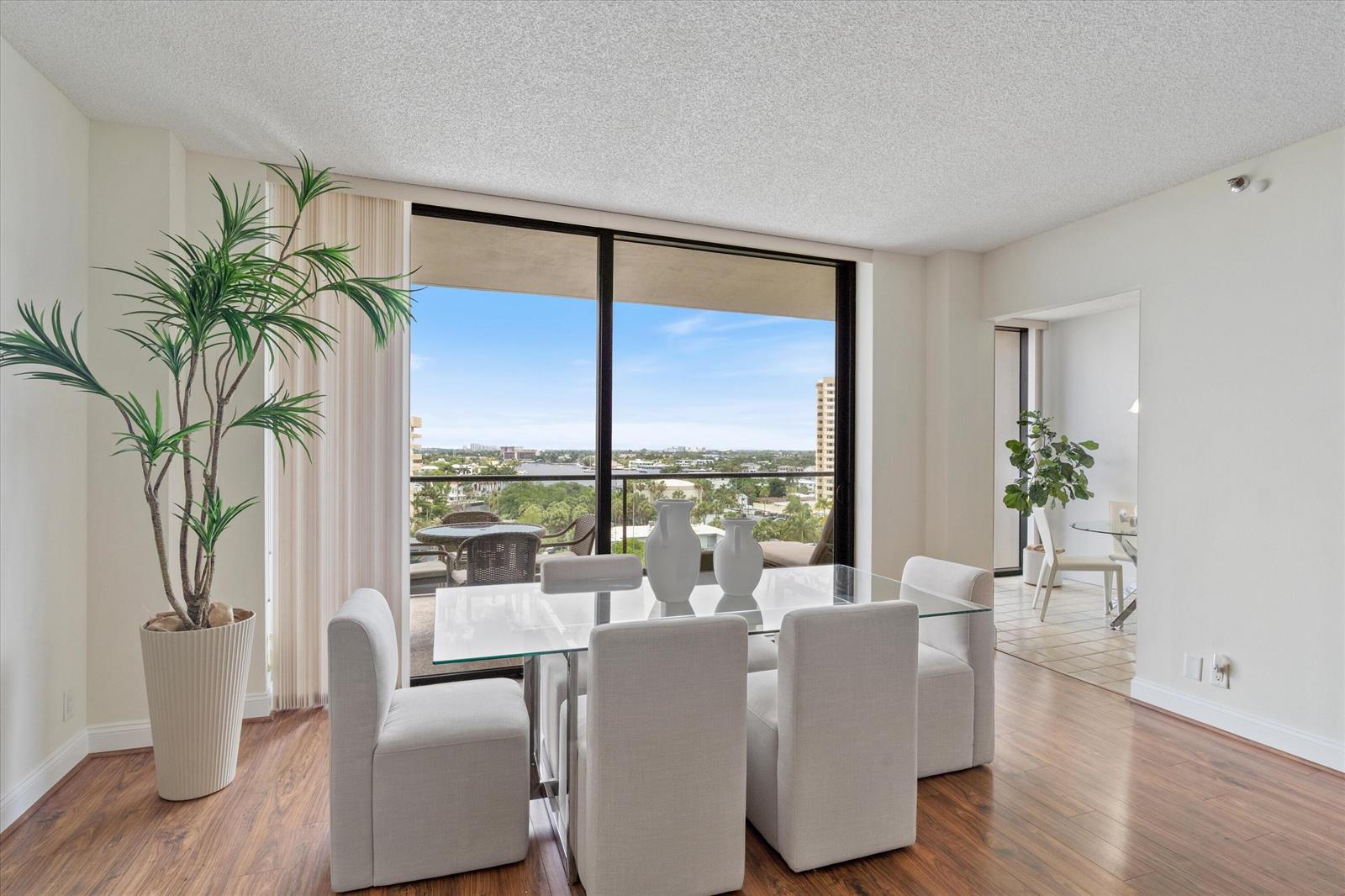 A dining room with a glass table, upholstered chairs, wood flooring, and a balcony view — 1300 S Ocean Boulevard # 705, Pompano Beach FL 33062, POMPANO BEACH, FL