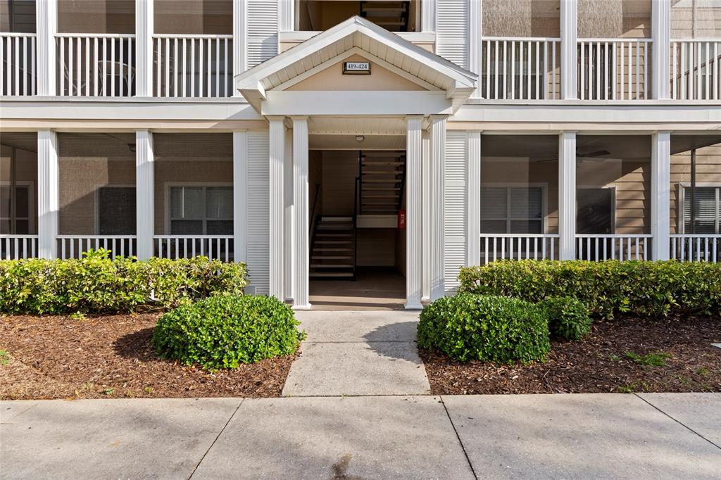 A ground-level view of an apartment building entrance with a staircase and screened-in porches — 4802 51ST STREET W UNIT 423, BRADENTON, FL