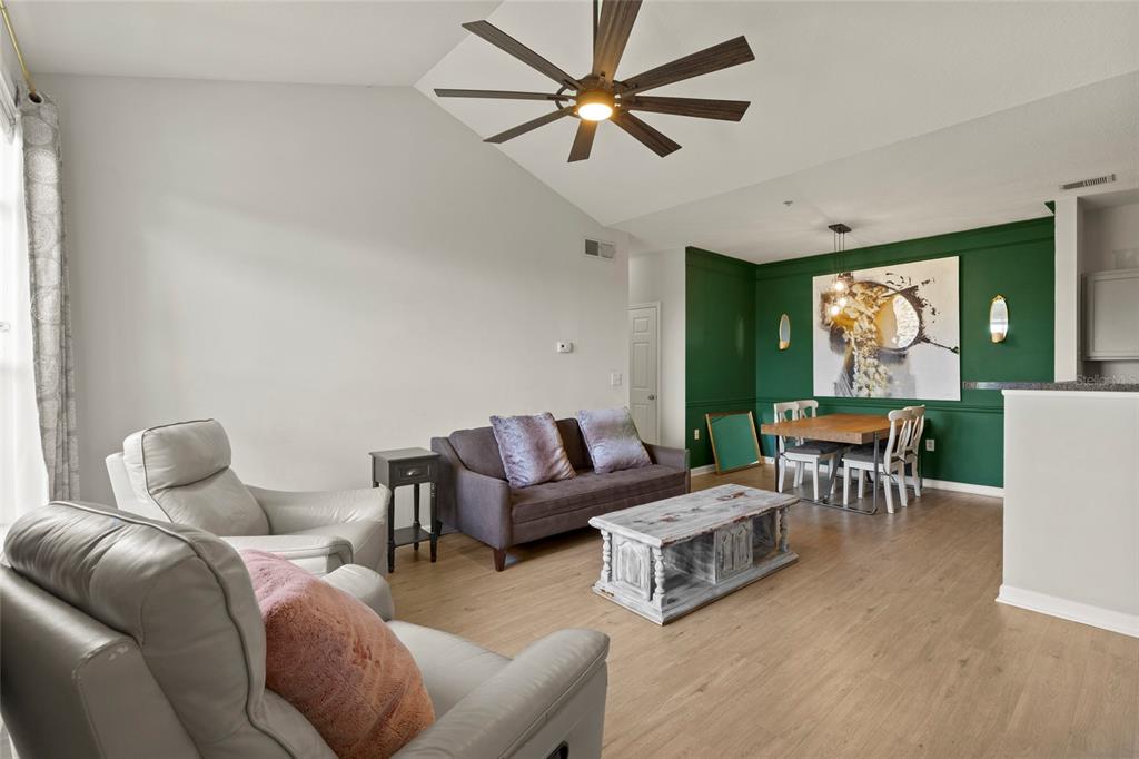 A living and dining area with light wood floors, a green accent wall, and ceiling fan — 4802 51ST STREET W UNIT 423, BRADENTON, FL