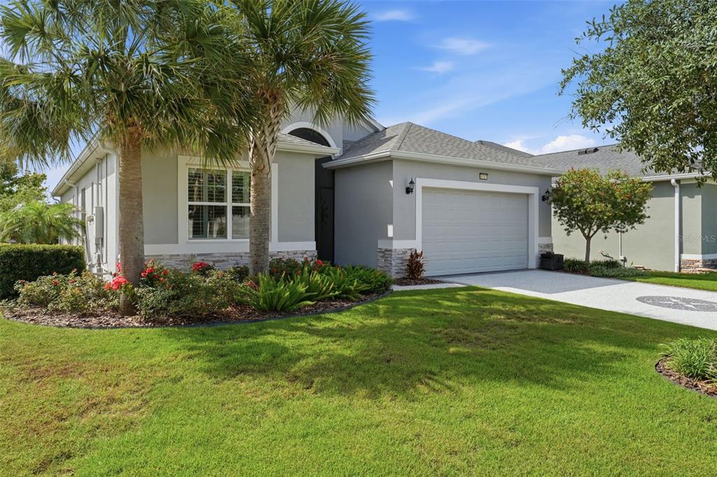 A single-story house with a gray exterior, a two-car garage, and a palm tree — 8707 PROVIDENCE CT, MOUNT DORA, FL