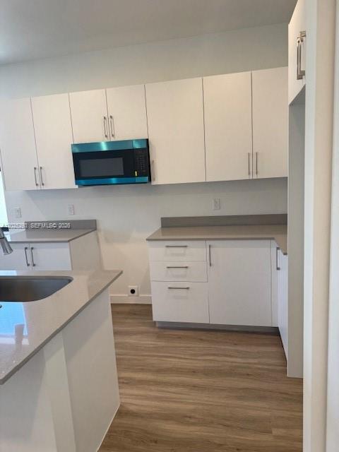 A modern kitchen features white cabinets, light countertops, and a built-in microwave — FLORIDA CITY, FL
