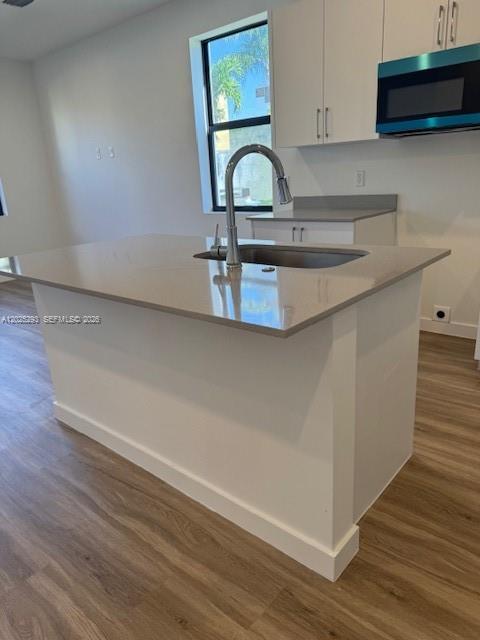 A kitchen island with a sink and light-colored countertops sits in a modern kitchen — FLORIDA CITY, FL
