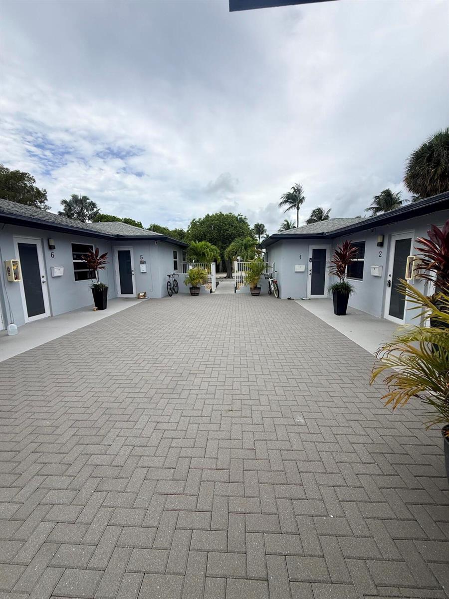 A paved courtyard sits between two single-story buildings with numbered doors and potted plants — 220 Walton Boulevard Unit 2, West Palm Beach FL 33405, WEST PALM BEACH, FL