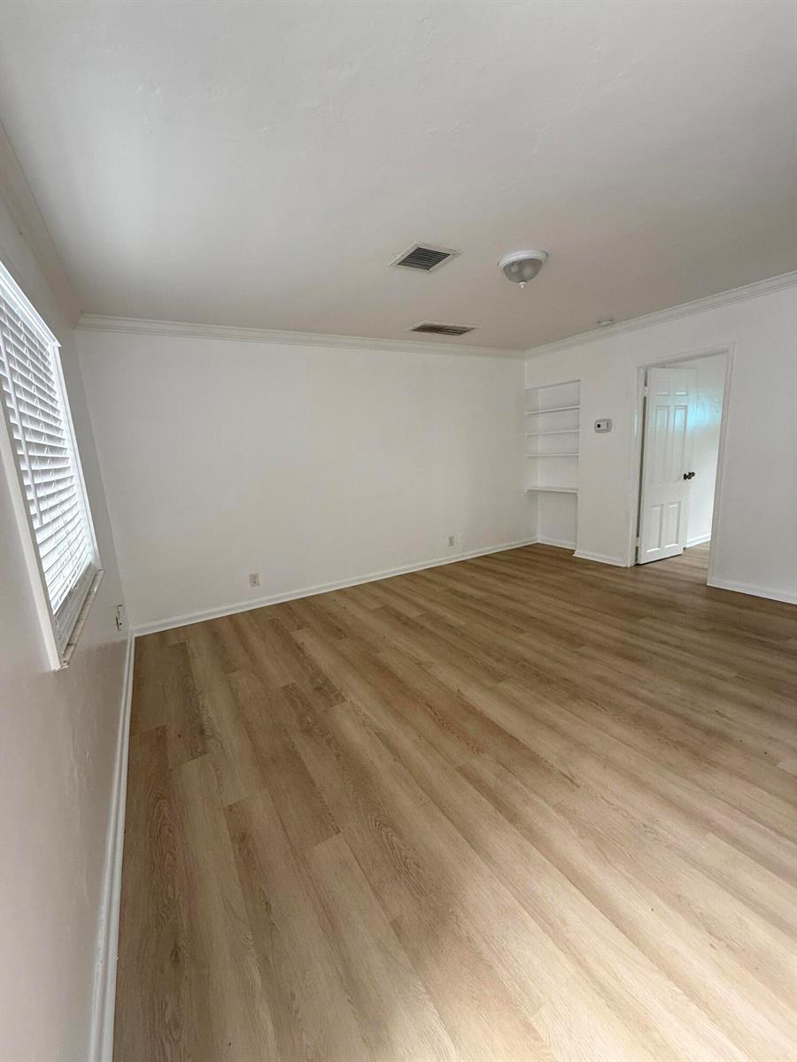 An empty room with light wood-look flooring, white walls, built-in shelving, and a doorway — 220 Walton Boulevard Unit 2, West Palm Beach FL 33405, WEST PALM BEACH, FL