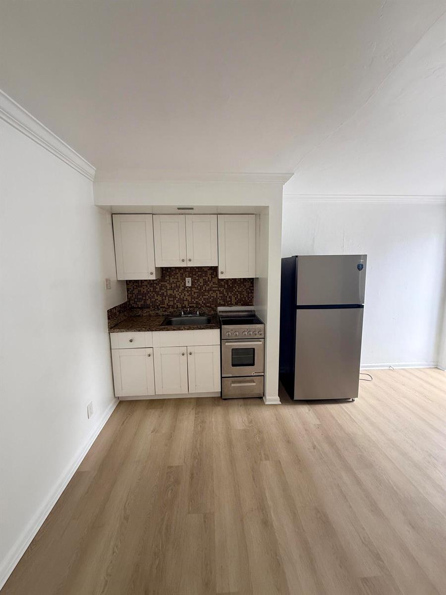 A small kitchen features white cabinets, a stainless steel stove, and a stainless steel refrigerator — 220 Walton Boulevard Unit 2, West Palm Beach FL 33405, WEST PALM BEACH, FL