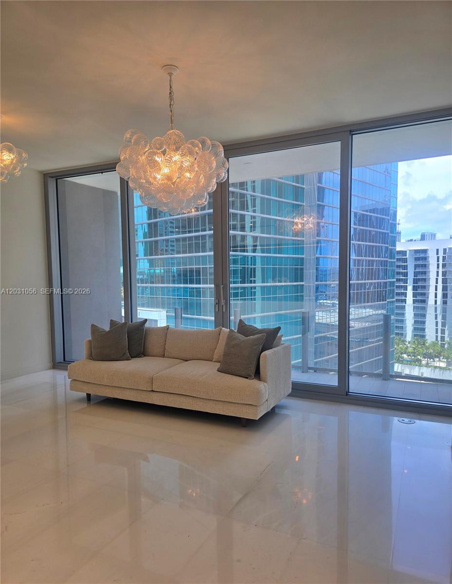 A modern living room features a bubble chandelier, a beige sofa, and floor-to-ceiling windows — 300 Biscayne Blvd Way # 2408W, Miami FL 33131, MIAMI, FL