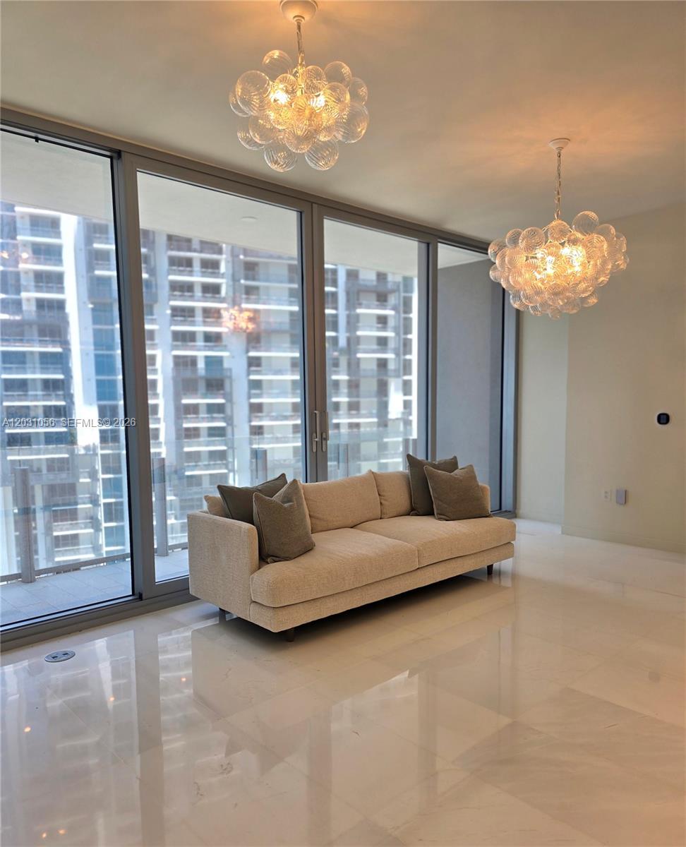 A modern living room features a beige sofa, two bubble chandeliers, and floor-to-ceiling windows — 300 Biscayne Blvd Way # 2408W, Miami FL 33131, MIAMI, FL