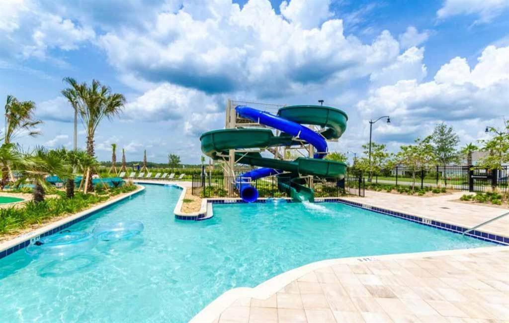 A swimming pool features a large blue and green water slide and lounge chairs nearby — 3150 PARADOX CIRCLE UNIT 305, KISSIMMEE, FL