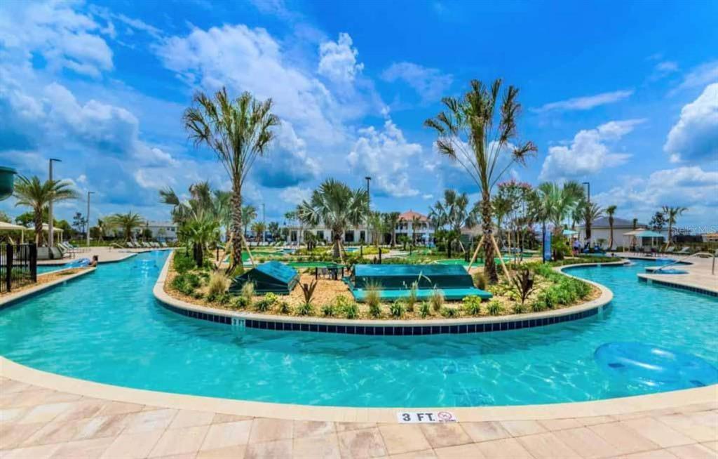 A lazy river pool with palm trees and landscaping surrounds a central island area — 3150 PARADOX CIRCLE UNIT 305, KISSIMMEE, FL