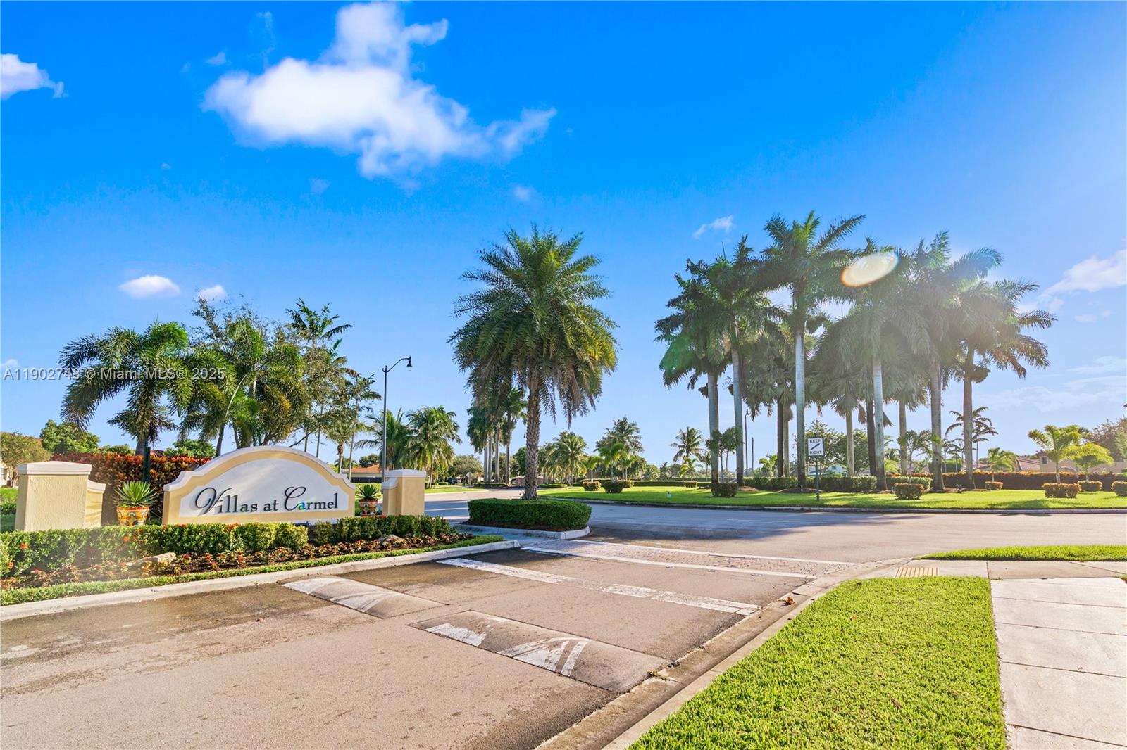 The entrance to the Villas at Carmel features a sign, palm trees, and paved roads — 1398 NE 33rd Ave # 25, Homestead FL 33033, HOMESTEAD, FL