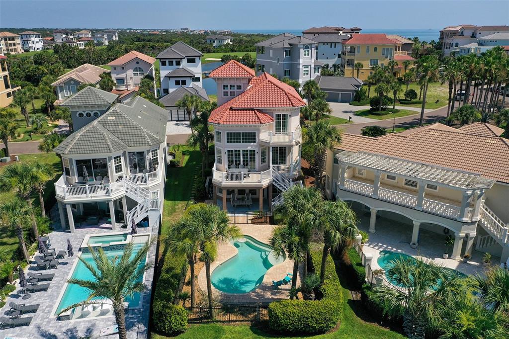 An aerial view shows three multi-story coastal homes with private swimming pools and palm trees — 29 NORTHSHORE AVENUE, PALM COAST, FL