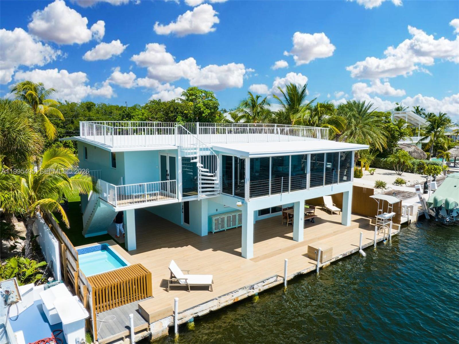 An elevated light blue waterfront house features a rooftop deck, spiral staircase, and private pool — 188 Orange Blossom Rd, Tavernier FL 33070, TAVERNIER, FL