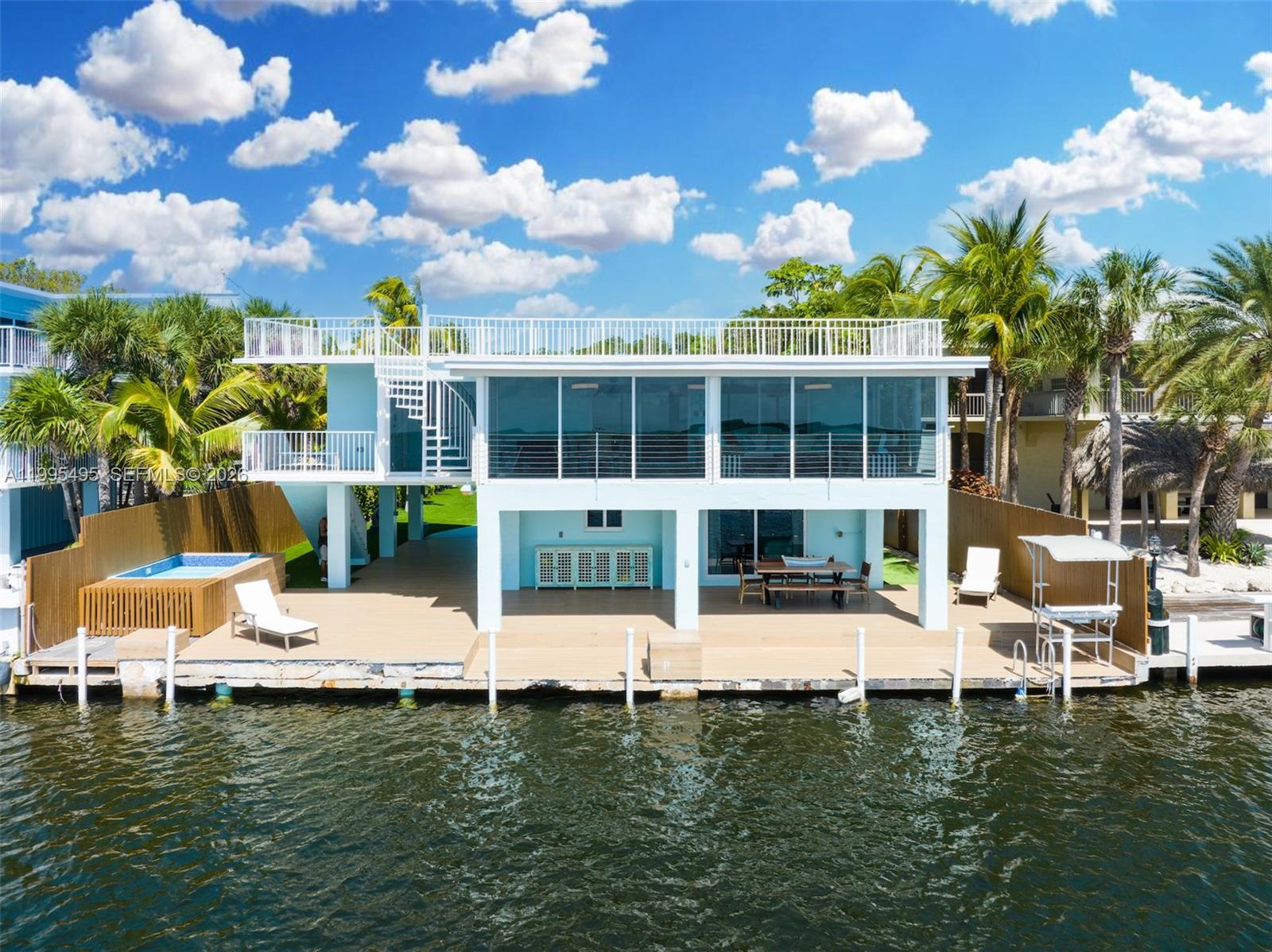 A two-story waterfront house features a rooftop deck, a ground-level patio, and a private dock — 188 Orange Blossom Rd, Tavernier FL 33070, TAVERNIER, FL