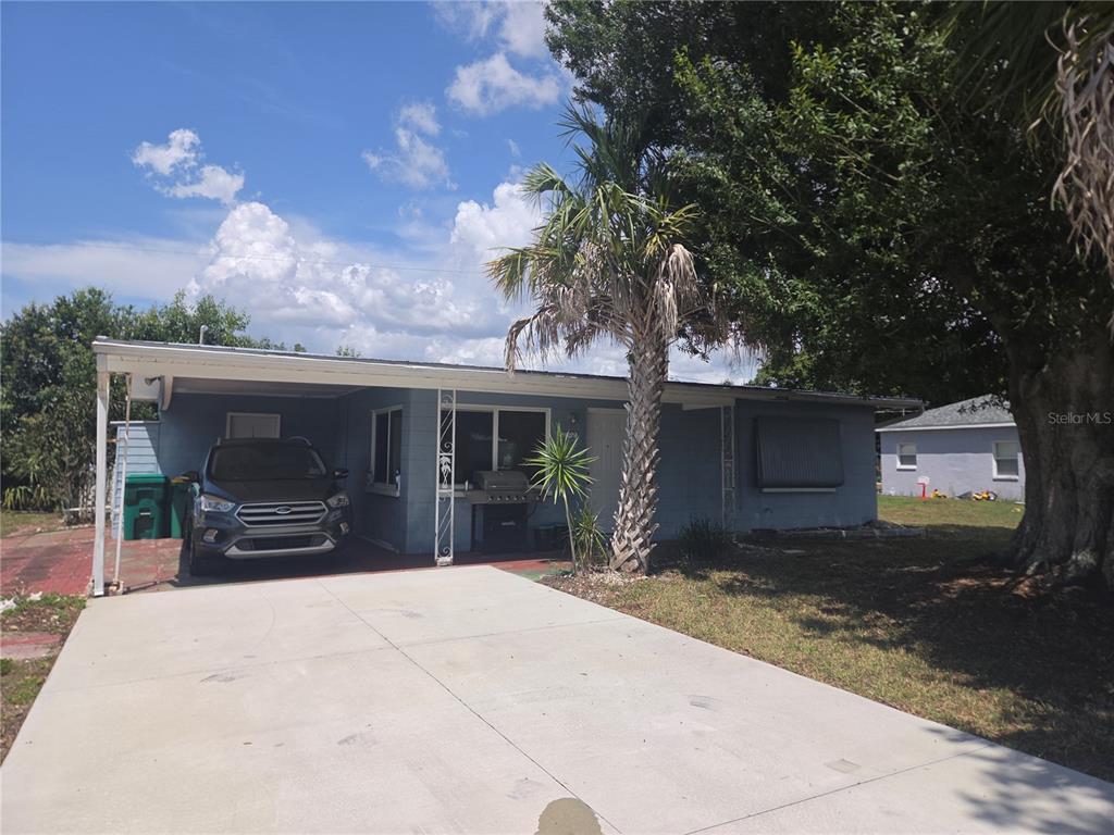 A single-story blue house with a carport, a concrete driveway, and a palm tree — 11192 3RD AVENUE, PUNTA GORDA, FL