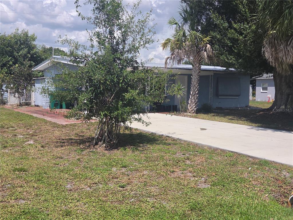 A single-story blue house with a concrete driveway and a palm tree in the front yard — 11192 3RD AVENUE, PUNTA GORDA, FL
