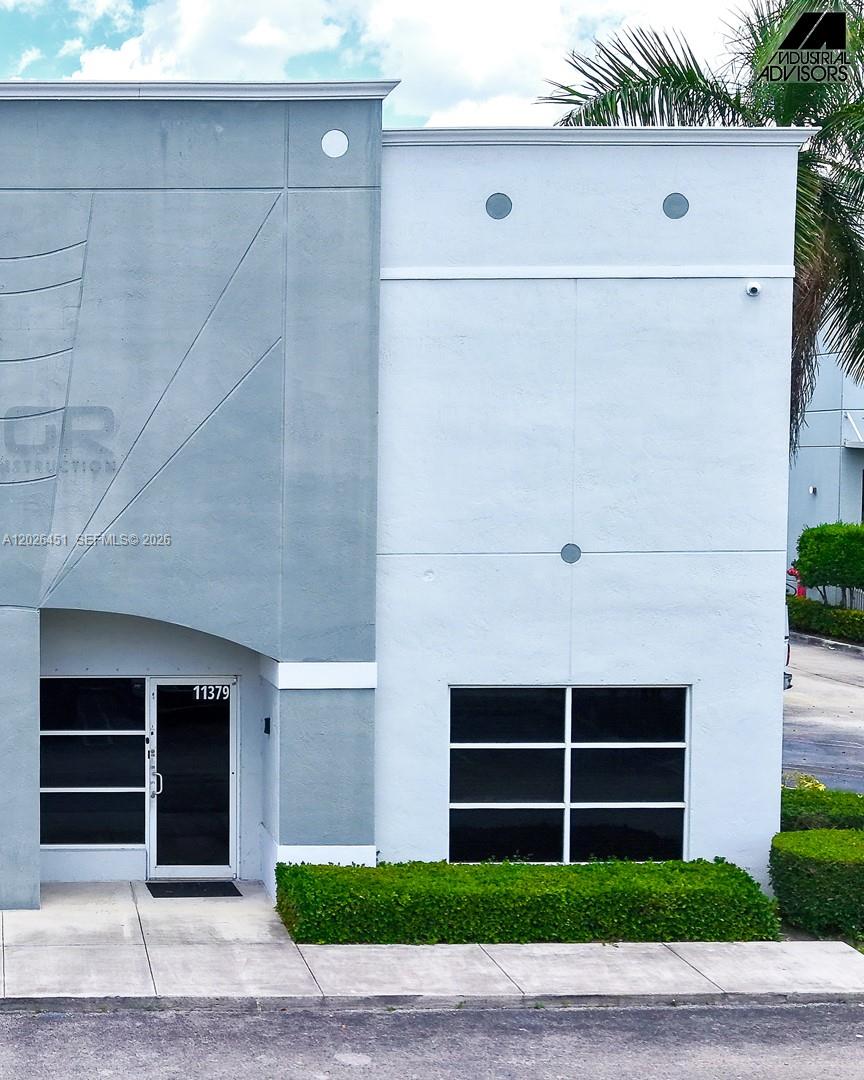 The exterior of a commercial building features a gray and white facade with glass doors — 11379 NW 122nd St # 11, Medley FL 33178, MEDLEY, FL