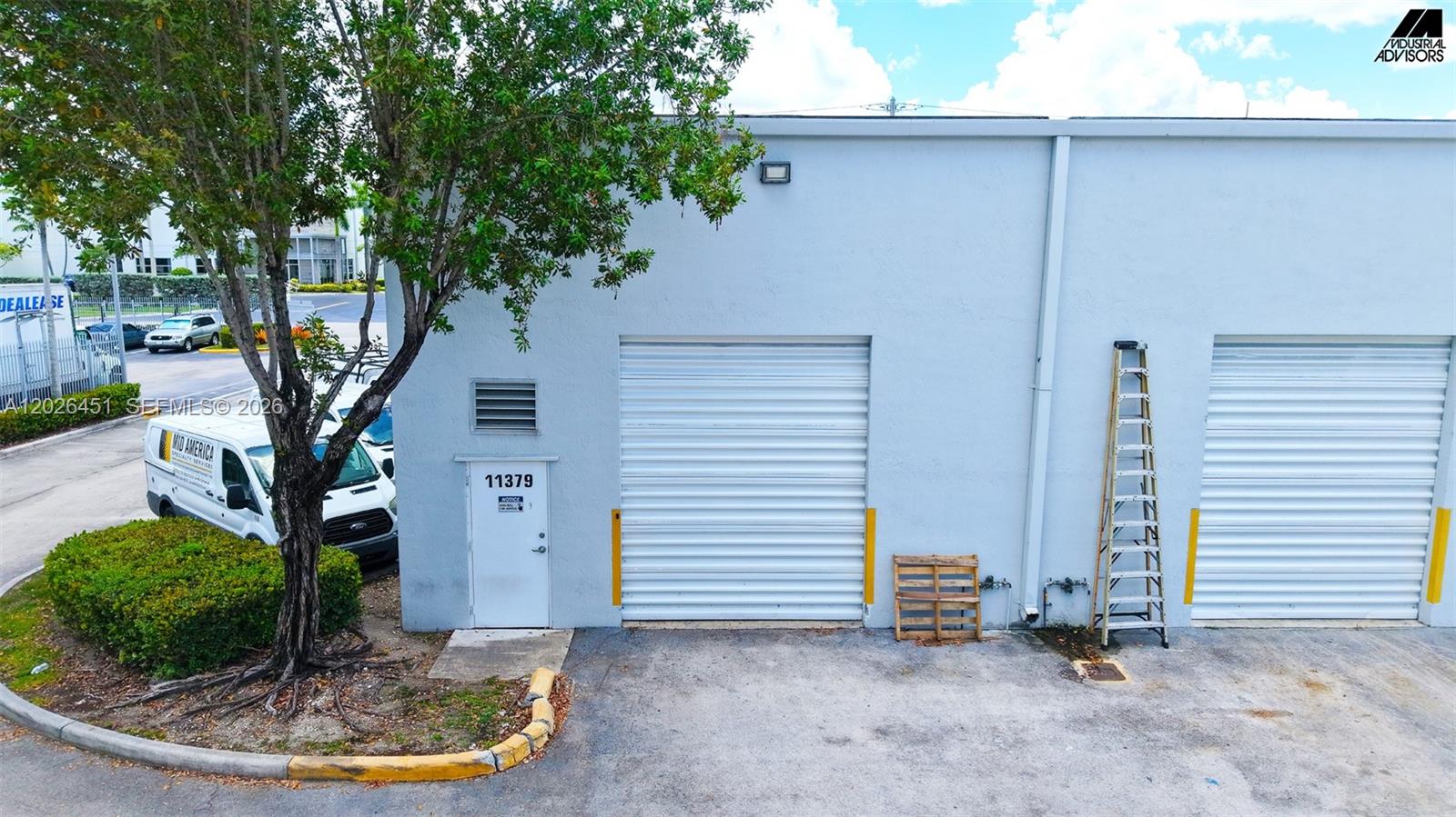 The exterior of a light gray industrial building features two roll-up doors and a pedestrian entrance — 11379 NW 122nd St # 11, Medley FL 33178, MEDLEY, FL