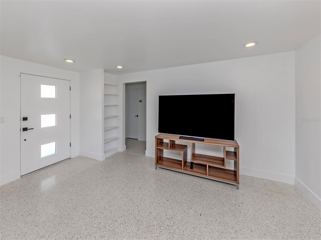 A white room with a front door, built-in shelving, a television console, and terrazzo flooring — 107 SORRENTO DRIVE, OSPREY, FL