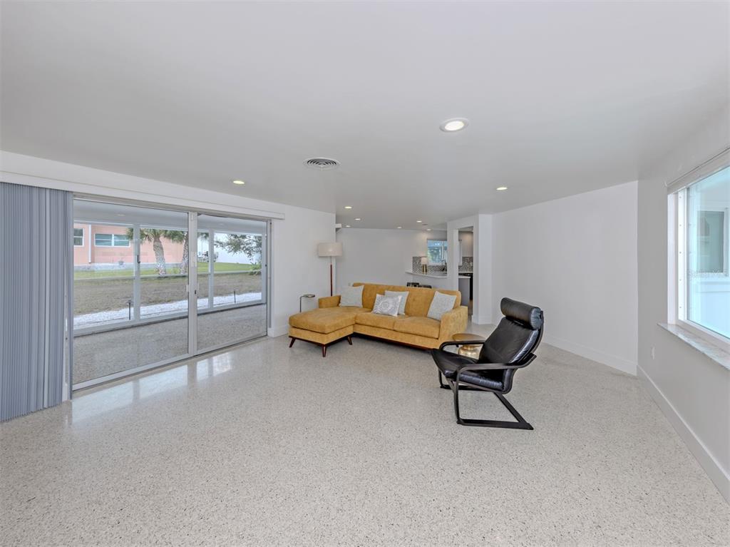 A living room features a yellow sectional sofa, a black lounge chair, and terrazzo flooring — 107 SORRENTO DRIVE, OSPREY, FL