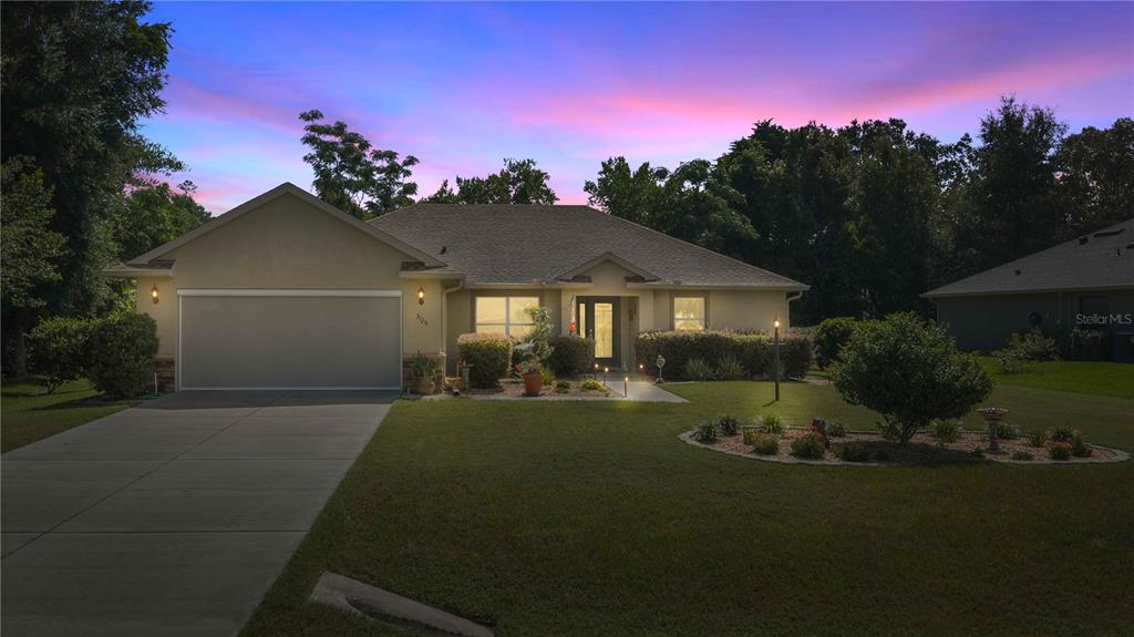 A single-story house with a two-car garage and a landscaped front yard at dusk — 3125 N CANTERBURY LAKE DRIVE, HERNANDO, FL