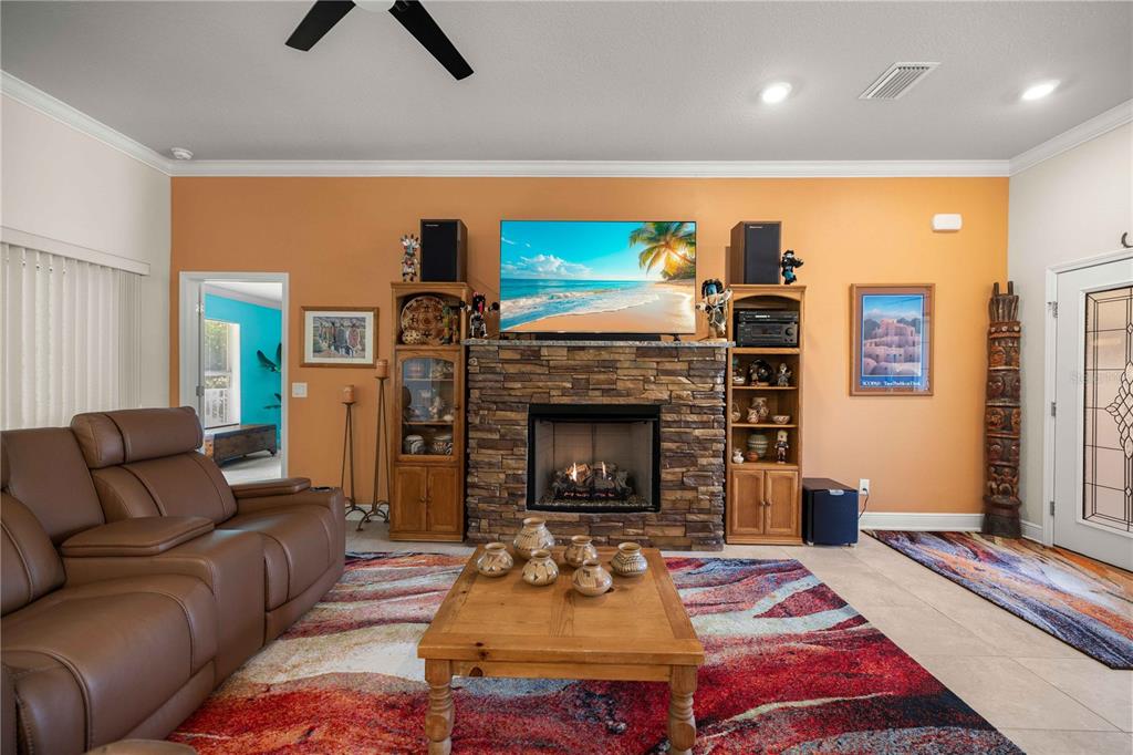 A living room features a stone fireplace, built-in shelving, a leather sofa, and a colorful rug — 3125 N CANTERBURY LAKE DRIVE, HERNANDO, FL