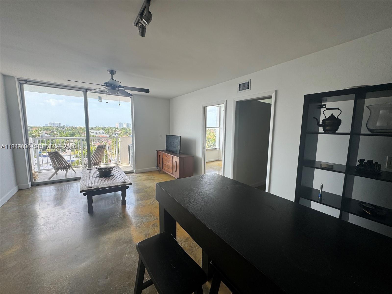 A living room with concrete floors, a ceiling fan, and a balcony with outdoor seating — 2000 NE 135th St # 606, North Miami FL 33181, NORTH MIAMI, FL