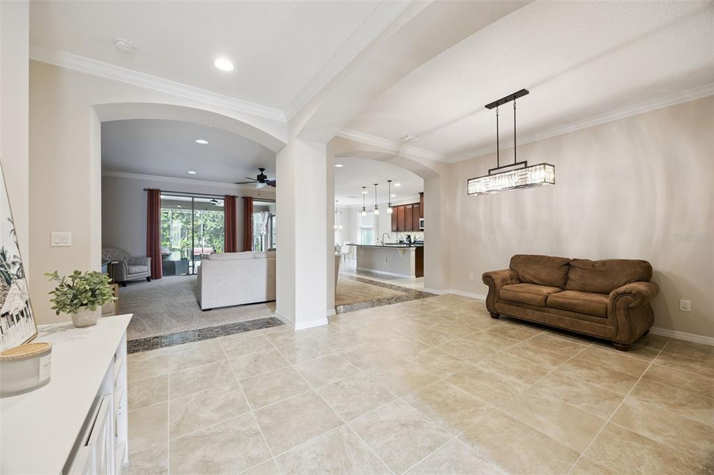 A tiled dining area features a brown sofa and a modern rectangular chandelier — 588 AUTUMN ASH DRIVE, CLERMONT, FL