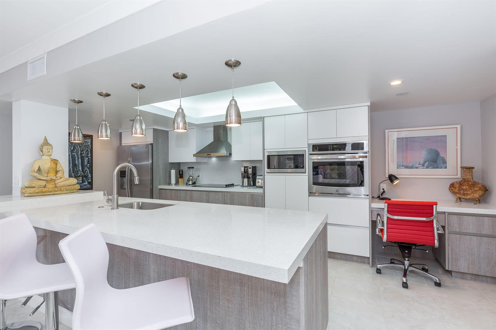 A modern kitchen features a white quartz island, stainless steel appliances, and a red office chair — 2455 Lindell Boulevard # 3304, Delray Beach FL 33444, DELRAY BEACH, FL